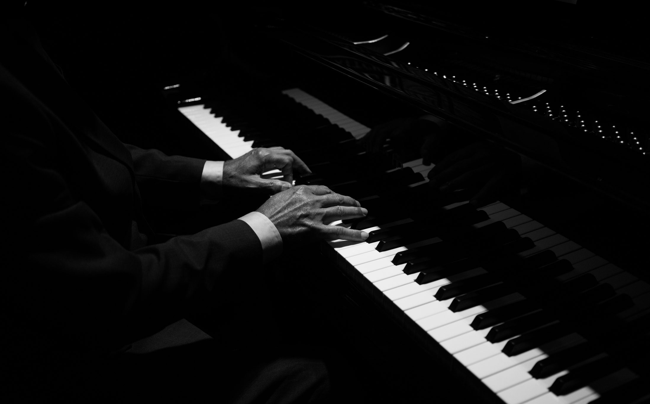 Hands playing piano in dim light
