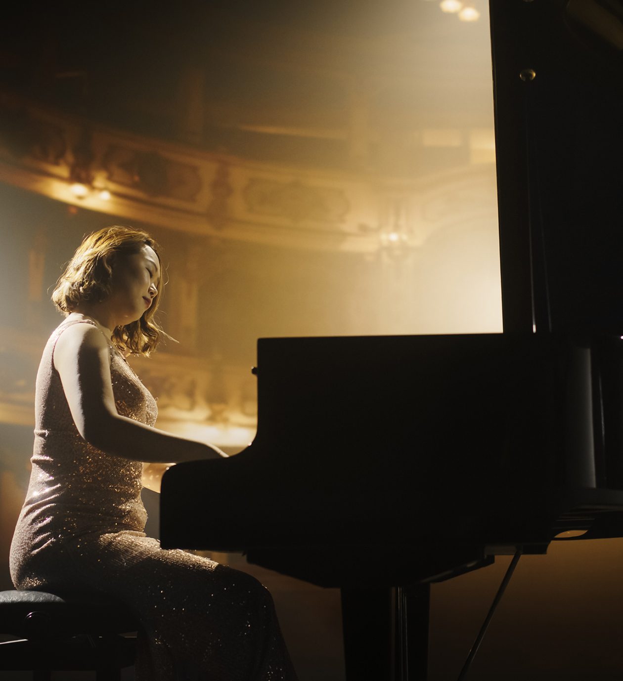 Pianist performing on stage in elegant dress.