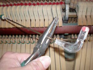Close-up of piano tuning using a tuning lever and mute.