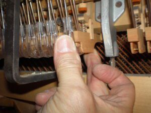 Hand repairing or tuning piano hammers inside a piano.
