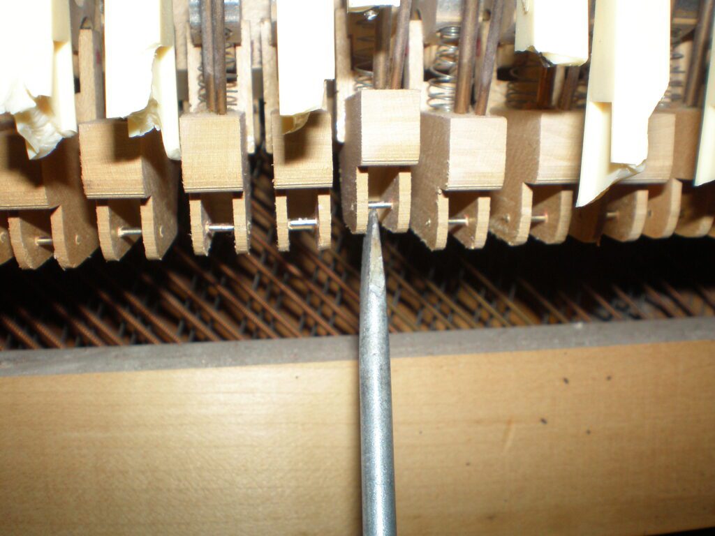 Close-up of piano hammer mechanism and strings.