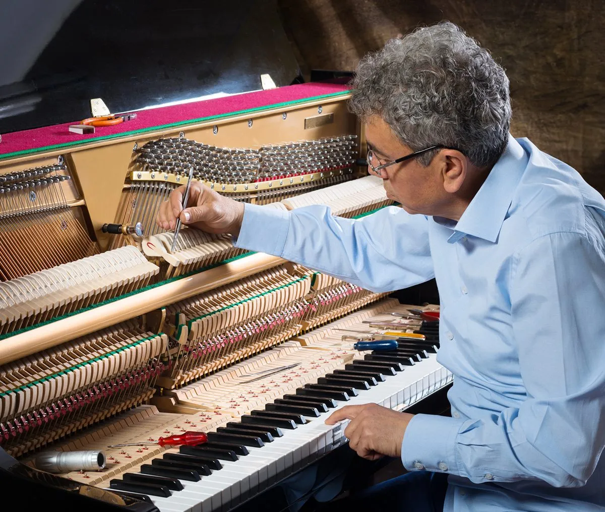 Man tuning a piano's internal strings